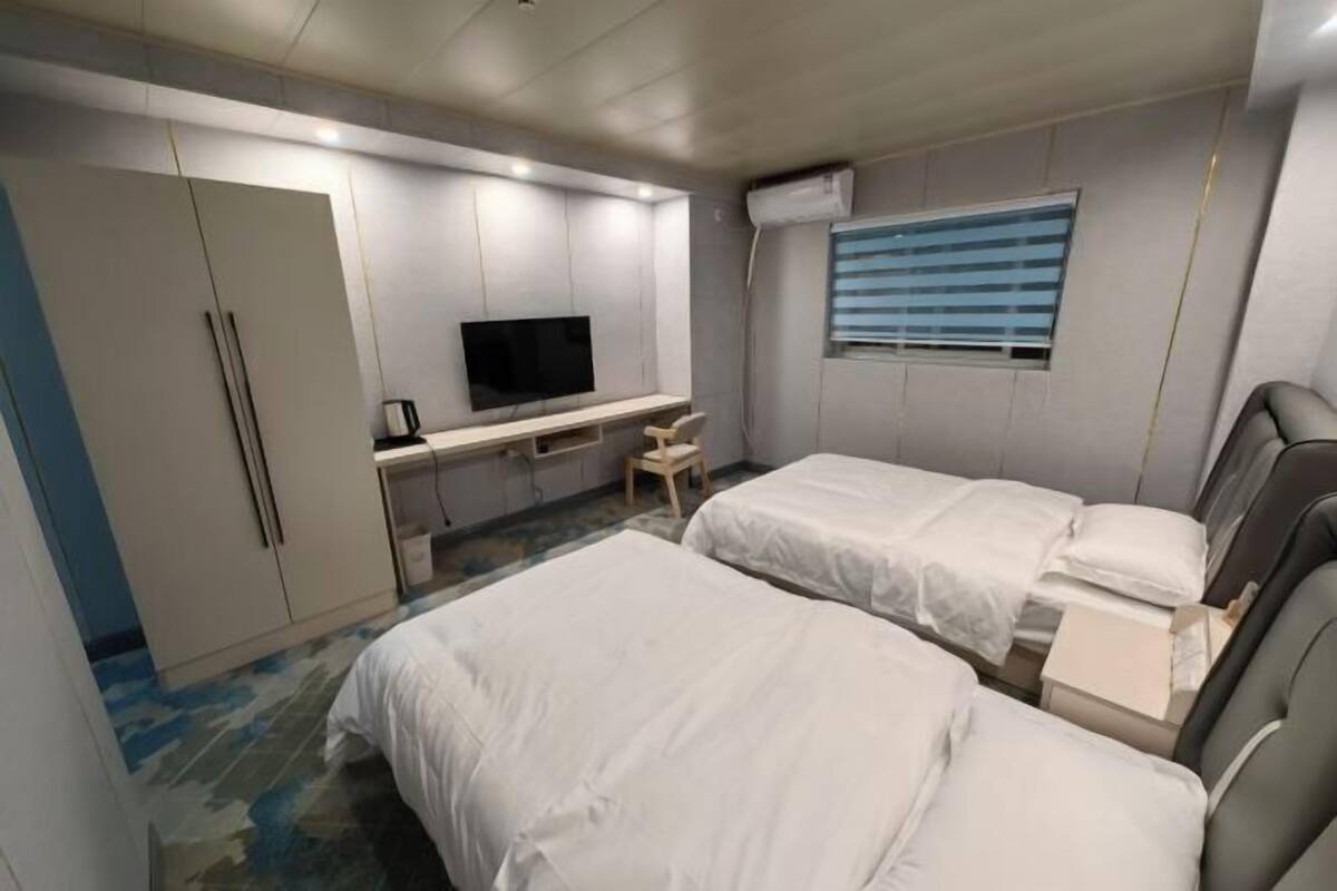 A hotel room with two beds, a TV, a desk, and a wardrobe.