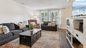 A living room with two sofas, a coffee table, and a TV stand. - Pet-Friendly Home with Fenced Yard, Monthly stays (Virginia Beach)