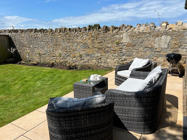 An outdoor seating area with wicker furniture and a stone wall backdrop.