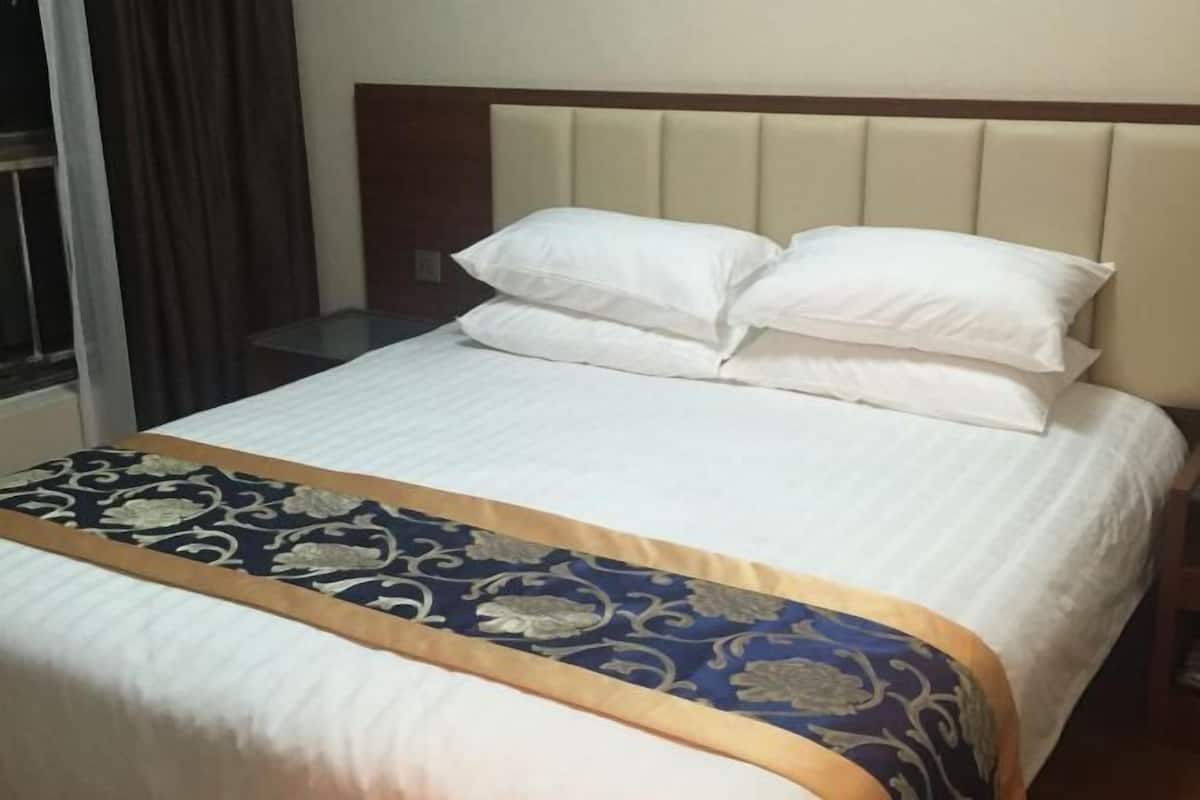 Une chambre d’hôtel avec un lit, une fenêtre avec des rideaux et une tête de lit.