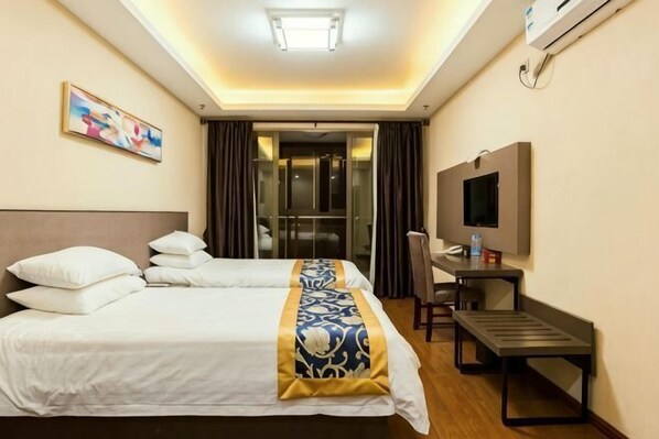 Ein Hotelzimmer mit einem Bett, einem Schreibtisch, einem Sessel, einem Fernseher und einer Tür, die auf einen Balkon führt.