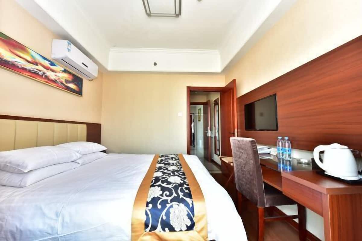 Une chambre d’hôtel avec un lit, un bureau, une chaise, une télévision et un tableau au mur.