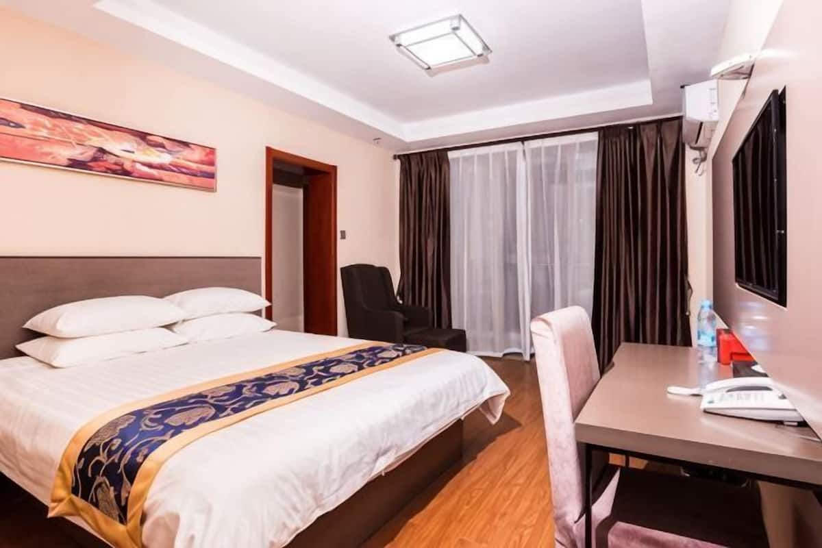 Une chambre d’hôtel équipée d’un lit, d’un bureau, d’une chaise, d’une télévision et d’un appareil de climatisation.
