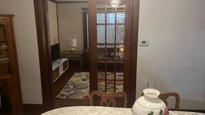 Un comedor con una mesa redonda, sillas, un jarrón decorativo y una alfombra estampada.