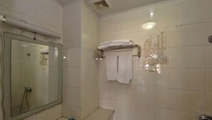 Un baño con un espejo grande, un lavabo y un perchero con toallas dobladas.