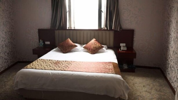 Una habitación de hotel con una cama grande, dos mesitas de noche y un ventanal con cortinas.