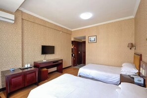 A hotel room with two beds, a desk, a television, and a door leading to another room. - Hong Tai Yang Hotel (Yuhuan)