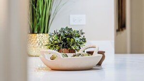 A kitchen with a white countertop, a potted plant, and two pendant lights.