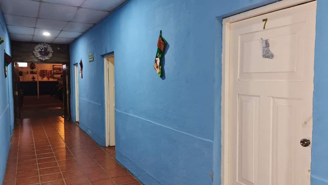 Un pasillo con paredes azules y una puerta blanca con el número 7.