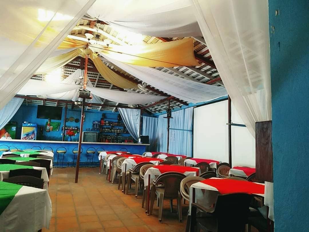 A restaurant with rows of tables, a bar area, and a blue wall with a mural.