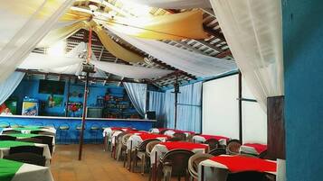 A restaurant with rows of tables, a bar area, and a blue wall with a mural.