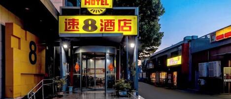 A hotel entrance with a prominent sign, a staircase, and a glass door.