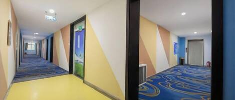 A hotel corridor with carpeted floors, doors, and a visible fire extinguisher.