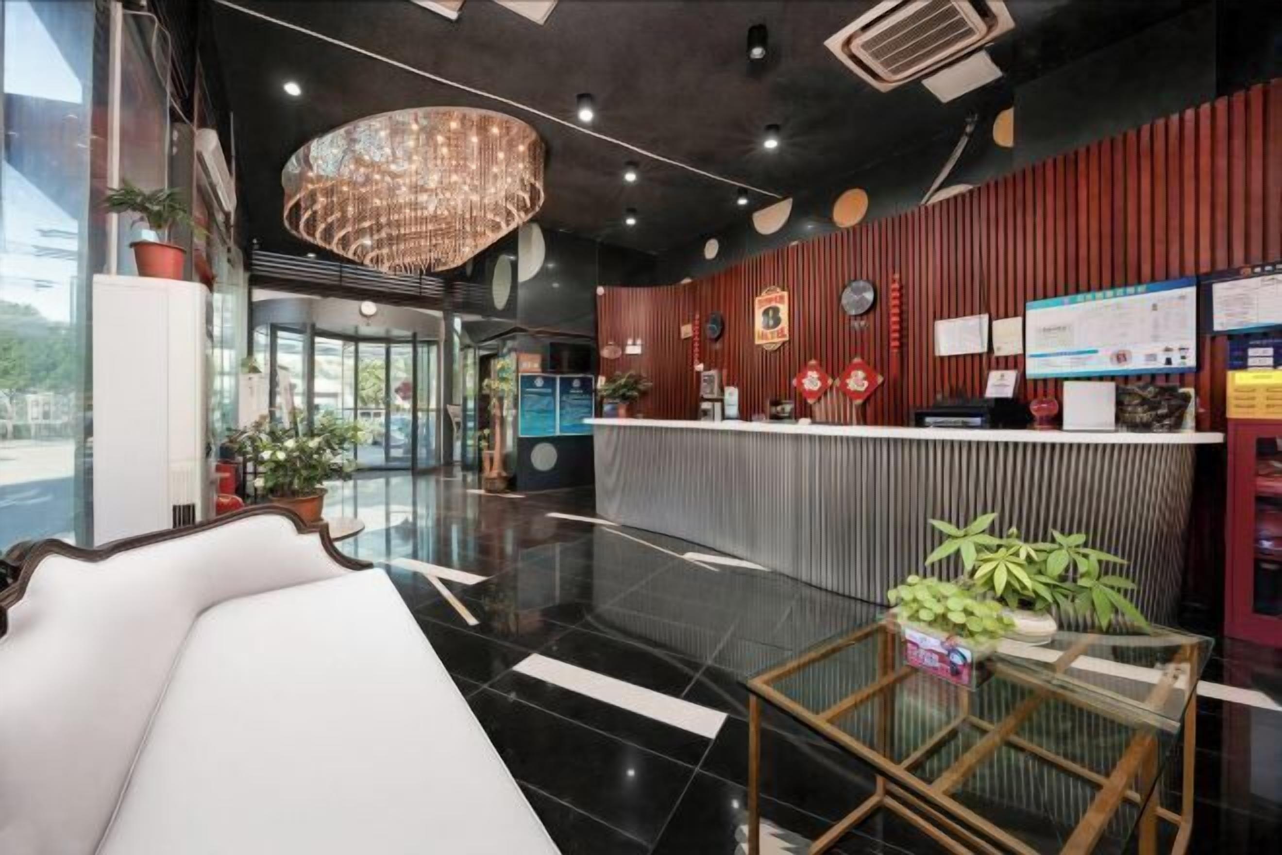 A hotel lobby with a reception desk, seating area, and a large chandelier.