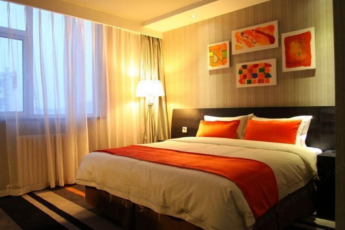 Ein Hotelzimmer mit Bett, Vorhängen, einer Lampe und Wandbildern.