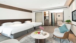 Moderni hotellihuone, jossa on kaksi sänkyä, ruokapöytä ja oleskelualue.