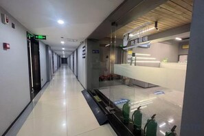 A hotel corridor with a reception desk, emergency exit signs, and fire extinguishers. - Sunshine Harbor Hotel (Xi'an Sunshine City) (Xi'an)