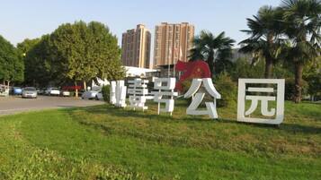 Placa com caracteres chineses, área gramada e palmeiras.