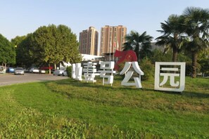 A sign with Chinese characters, a grassy area, and palm trees. - Sunshine Harbor Hotel (Xi'an Sunshine City) (Xi'an)