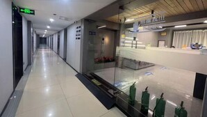 A hotel corridor with a reception desk, emergency exit sign, and fire extinguishers. - Sunshine Harbor Hotel (Xi'an Sunshine City) (Xi'an)