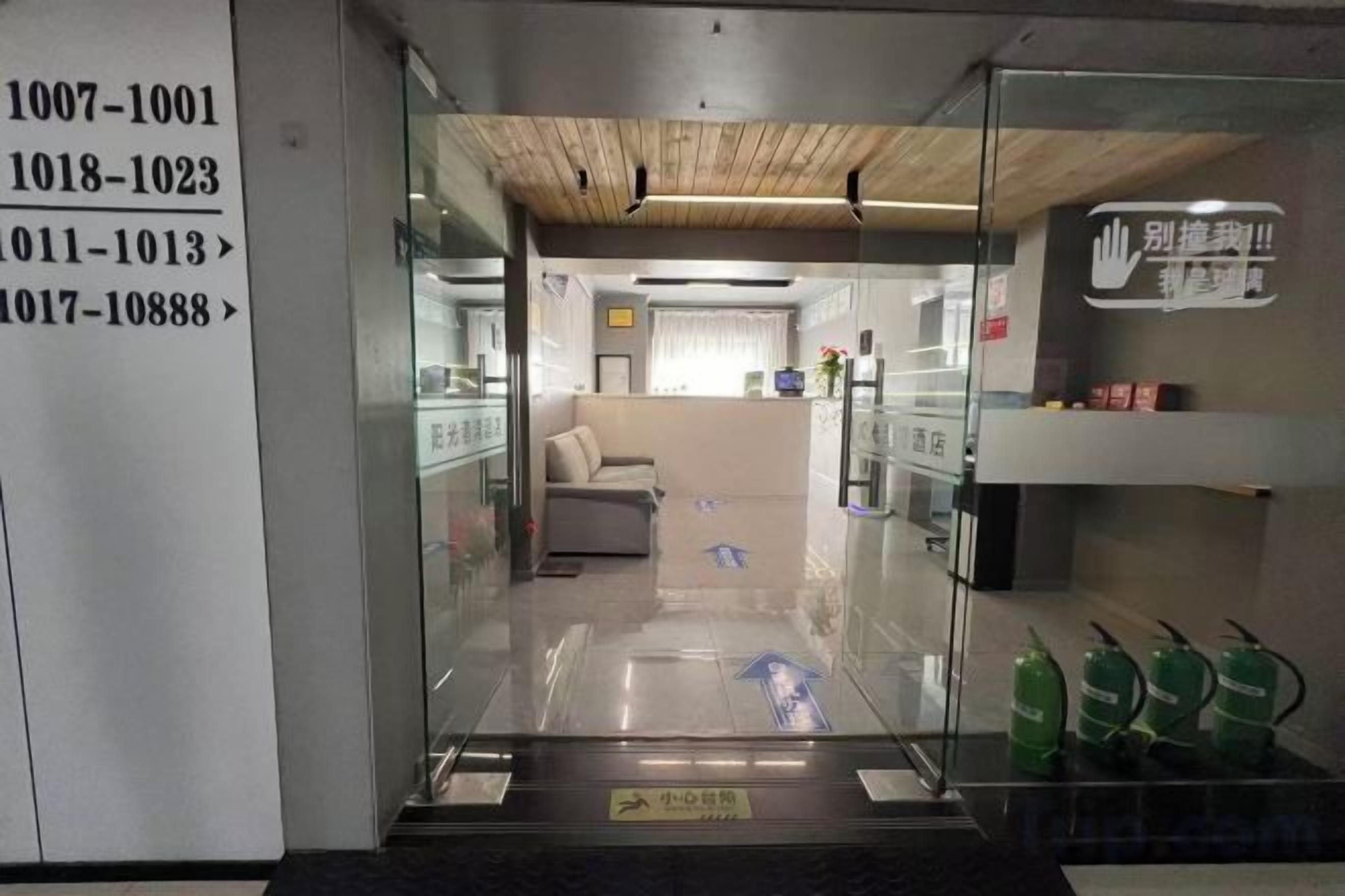 A hotel entrance with a reception desk, a sofa, and a fire extinguisher.