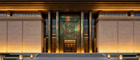 Entrada de un edificio con una puerta grande iluminada y columnas.