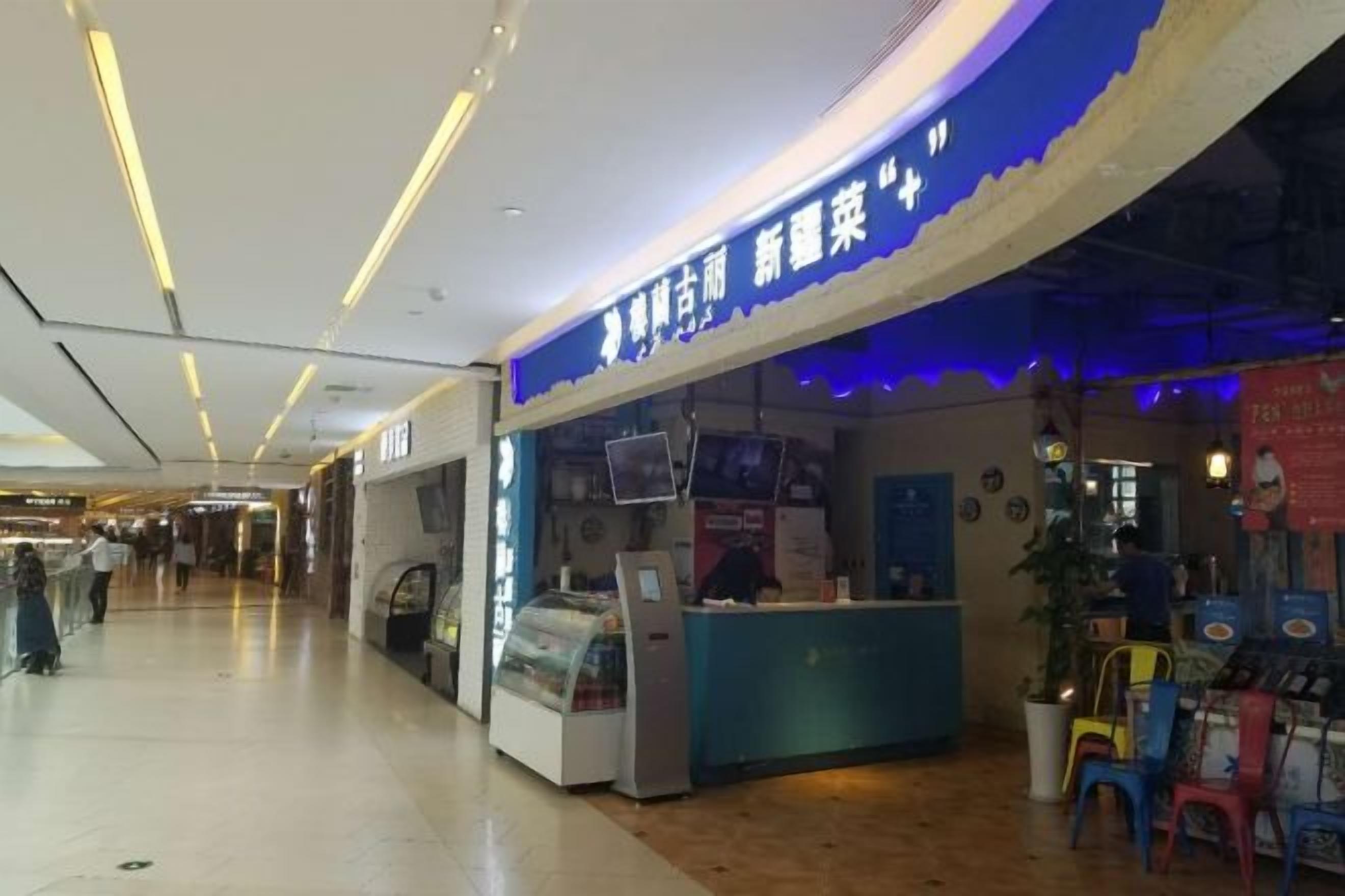 A food stall with a blue sign, a counter, and a display case in a shopping mall.
