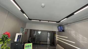 A reception area with a reception desk, a digital screen, and a glass partition.