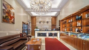 A lobby with a reception desk, a chandelier, a red carpet, and a display of items on shelves. - Zhuoyue Jiahao Hotel (Guiyang)