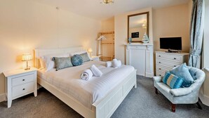 A neatly arranged bedroom with a bed, bedside tables, a chair, a television, and a mirror. - 2 Bed in Appledore (oc-s29561) (Appledore)