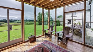 Um quarto espaçoso com grandes janelas que oferecem vista para um campo gramado e um edifício branco.