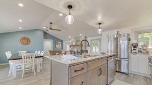 A spacious kitchen with a central island, stainless steel appliances, and a dining area with white chairs. - Sandy Bottoms....Higgins Lake 3 bedroom + Detached Bunkhouse (Roscommon)