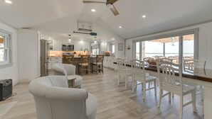 A spacious living area with a dining table and chairs, a ceiling fan, and a view through large windows. - Sandy Bottoms....Higgins Lake 3 bedroom + Detached Bunkhouse (Roscommon)