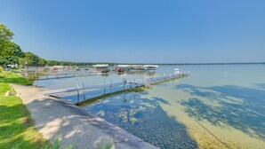 A calm lake with a dock and boats, surrounded by greenery and a clear sky. - Sandy Bottoms....Higgins Lake 3 bedroom + Detached Bunkhouse (Roscommon)