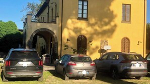 Eine Reihe geparkter Autos vor einem gelben Gebäude mit Bogenportal und Balkon.