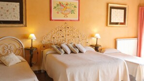 Ein Hotelzimmer mit zwei Betten, jeweils mit weißem Kopfteil und einem Nachttisch mit Lampe. Darüber an der Wand hängt ein gerahmtes Bild mit Obst.
