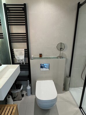 A modern bathroom with a toilet, sink, and towel rack. - The Rabbit Hole Lovely, Spacious Studio Flat in Shepherd’s Bush (London)