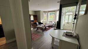 A spacious living room with a large window, a sofa, a coffee table, and a dining area.