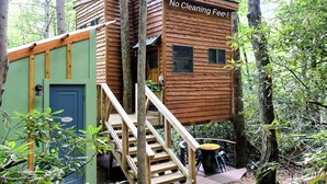 A treehouse with a "No Cleaning Free!" sign, wooden stairs, and a small deck area. - The Hidden Hemlock Treehouse your fall escape!  4x4 required. (Elizabethton)