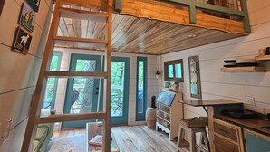 A rustic cabin interior with a loft bedroom, wooden floors, and a dining area with a wooden table and chairs. - The Hidden Hemlock Treehouse your fall escape!  4x4 required. (Elizabethton)