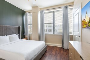 Ein Hotelzimmer mit einem großen Bett, einem Schreibtisch und einem Fenster mit Vorhängen.