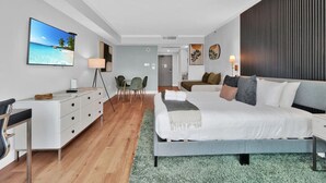Una habitación de hotel moderna con una cama grande, un escritorio, una silla, un televisor y vistas a la playa.