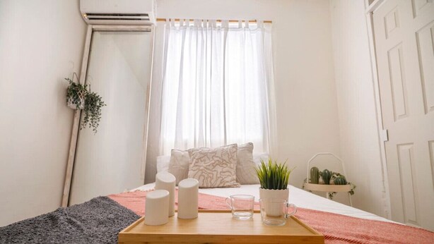 Ein ordentlich eingerichtetes Schlafzimmer mit einem Bett, Nachttisch und einem Fenster mit Vorhängen.