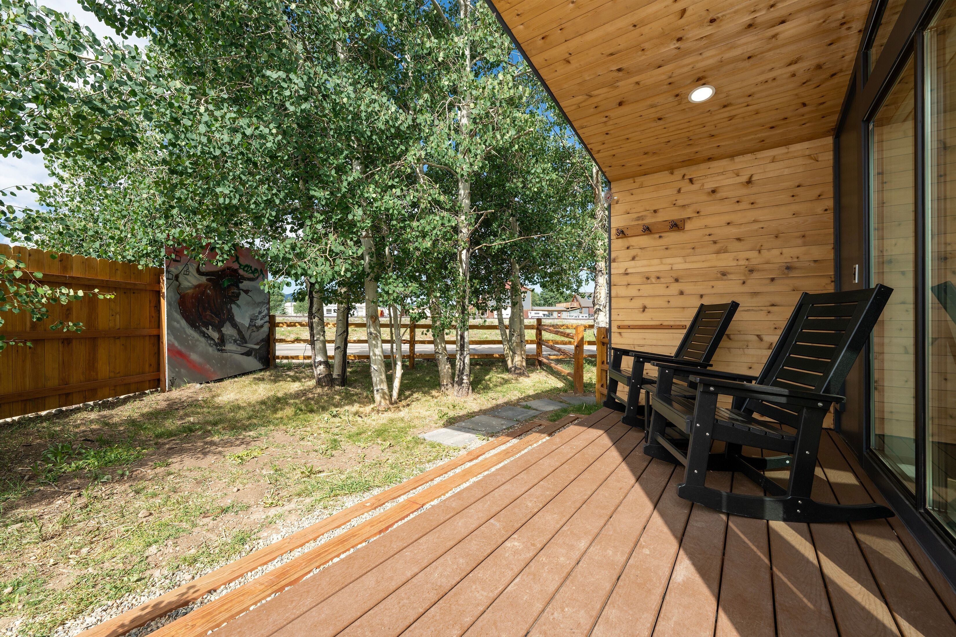 Une terrasse en bois avec deux chaises longues, un plafond en bois et une porte vitrée.