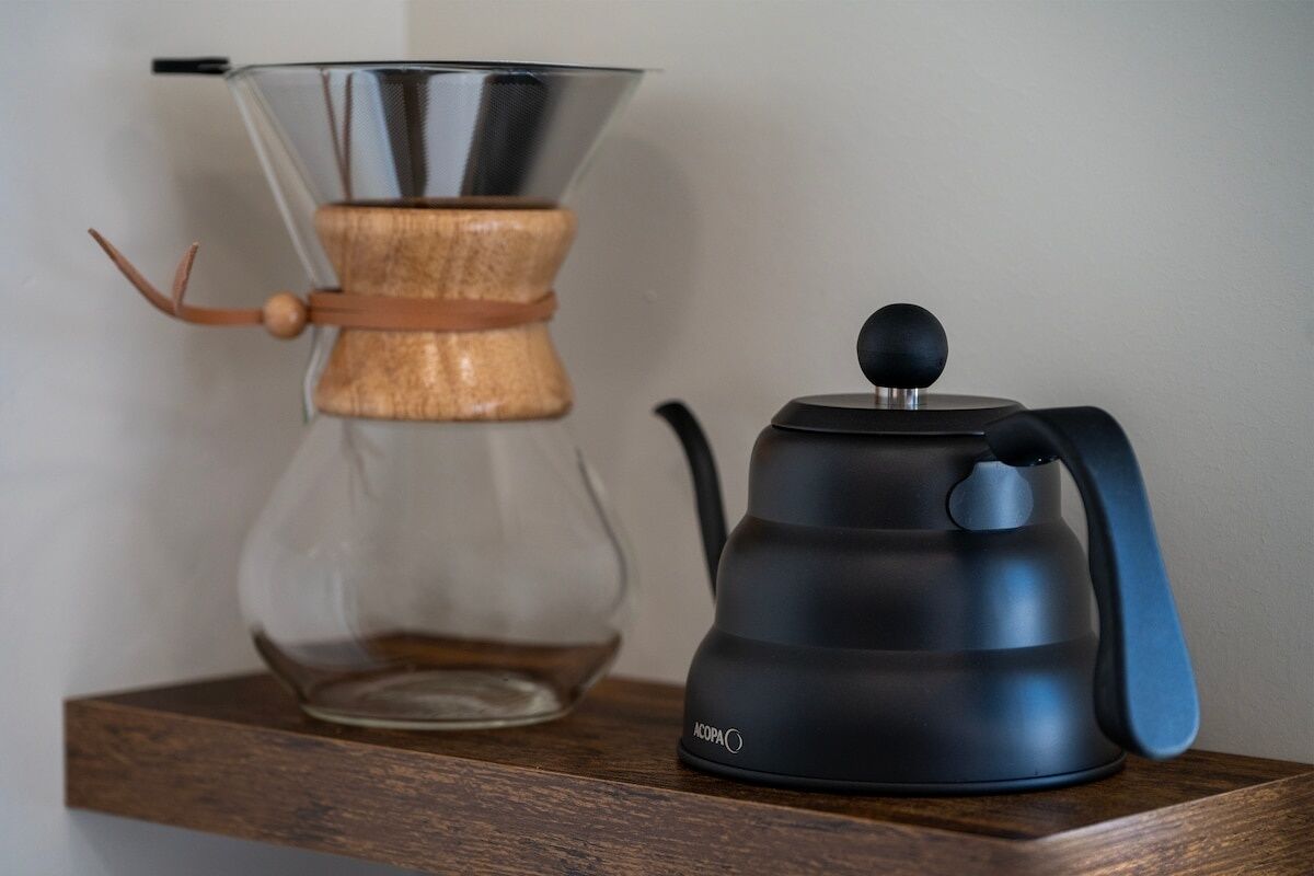 A coffee maker and a glass carafe on a wooden shelf.