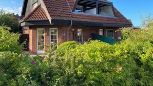 A two-story house with a sloped roof, brick exterior, and large windows. - Maisonette-wohnung mit Schönem Balkon in Deichnähe (Friedrichskoog)