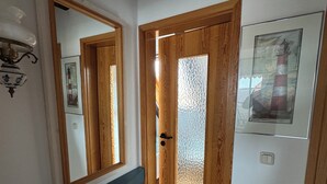 A hallway with a wooden door, a mirror, and a framed picture on the wall. - Maisonette-wohnung mit Schönem Balkon in Deichnähe (Friedrichskoog)