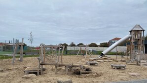 A playground with a slide, swings, and climbing structures. - Maisonette-wohnung mit Schönem Balkon in Deichnähe (Friedrichskoog)