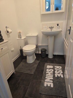 A bathroom with a toilet, sink, and a mirror above the sink. There is a towel rack with a towel and a trash can next to the toilet. - Emerald Apartments with A* star Proximity near all amenities. Pet friendly. (London)