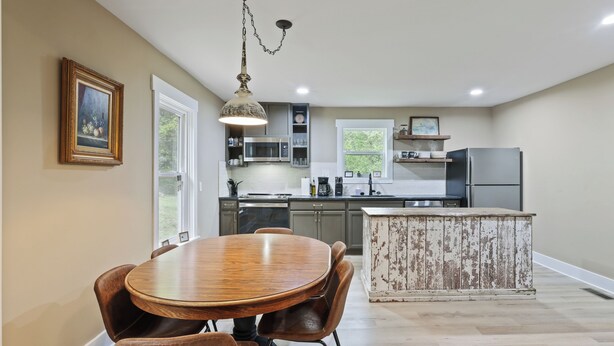 A modern kitchen with a wooden dining table, chairs, and a rustic island.